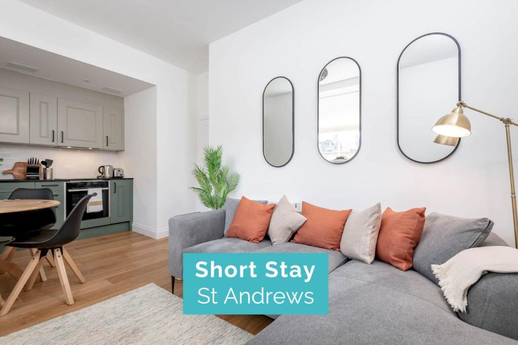 uma sala de estar com um sofá cinzento e seis espelhos em Skye Sands - The Eden Residence - St Andrews em St. Andrews