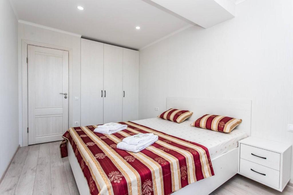 a white bedroom with a bed with a striped blanket at Starrent Testimiteanu Kaufland MallDova shopping mall in Chişinău