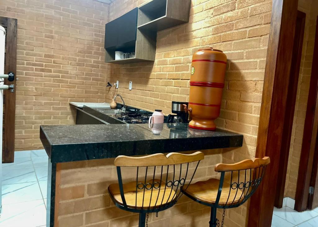 una cucina con bancone, due sedie e un apparecchio di Flat com 2 quartos 2 banh AR e uma vista espetacular na área central de GV com cozinha completa-Bom p grupos ou familias ou empresas a Governador Valadares
