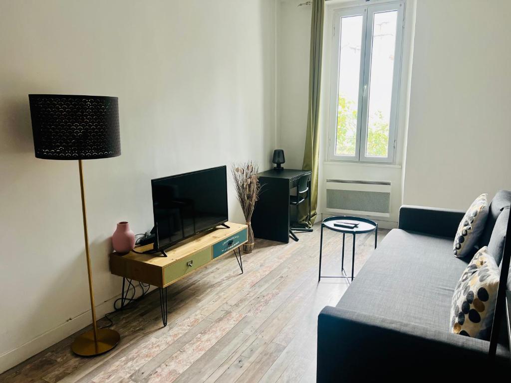 Il comprend un salon doté d'un canapé et d'une télévision à écran plat. dans l'établissement Appartement cosy deux pièces proche centre ville de Marseille, à Marseille