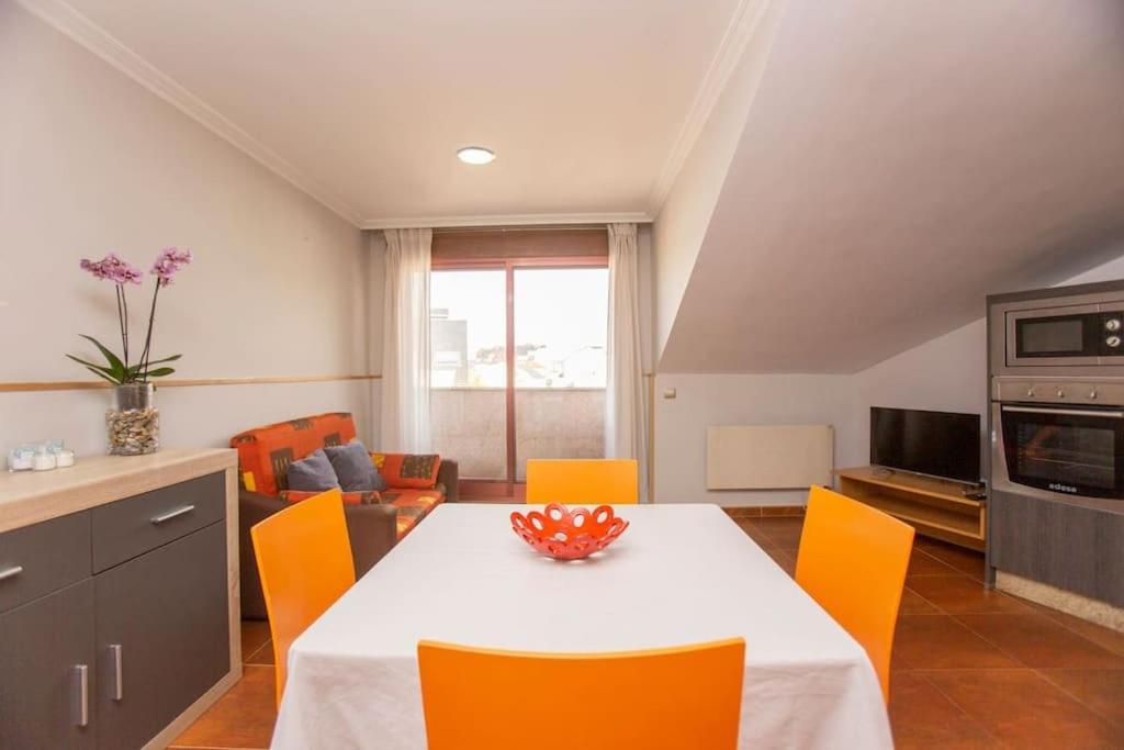een keuken met een tafel en oranje stoelen in een kamer bij Precioso ático en Sanxenxo in Sanxenxo