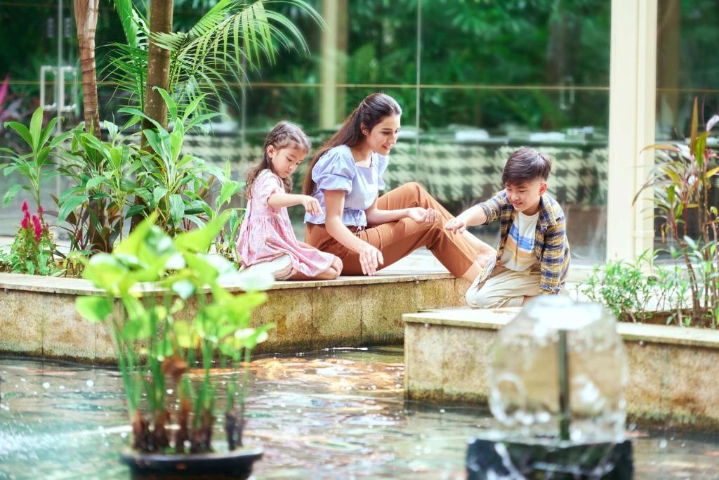 a woman and two children sitting next to a fountain at Shangri-La Kuala Lumpur in Kuala Lumpur