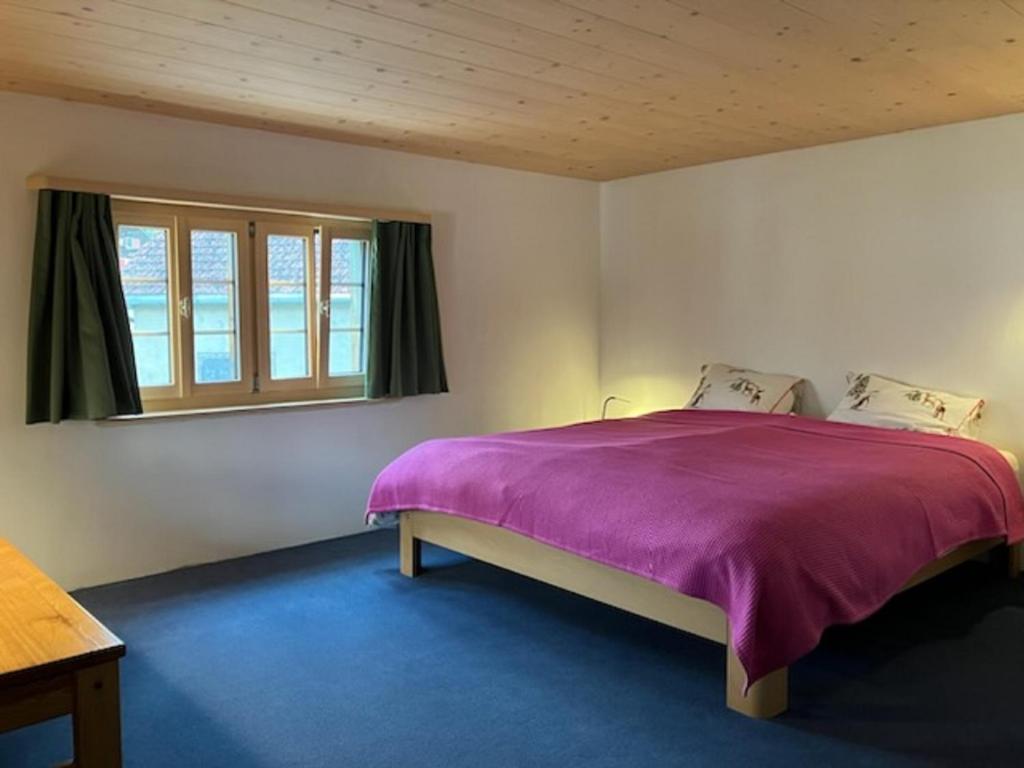- une chambre avec un lit violet et une fenêtre dans l'établissement Casa Vanellus / Vignogn / Val Lumnezia / near Laax, à Vigens