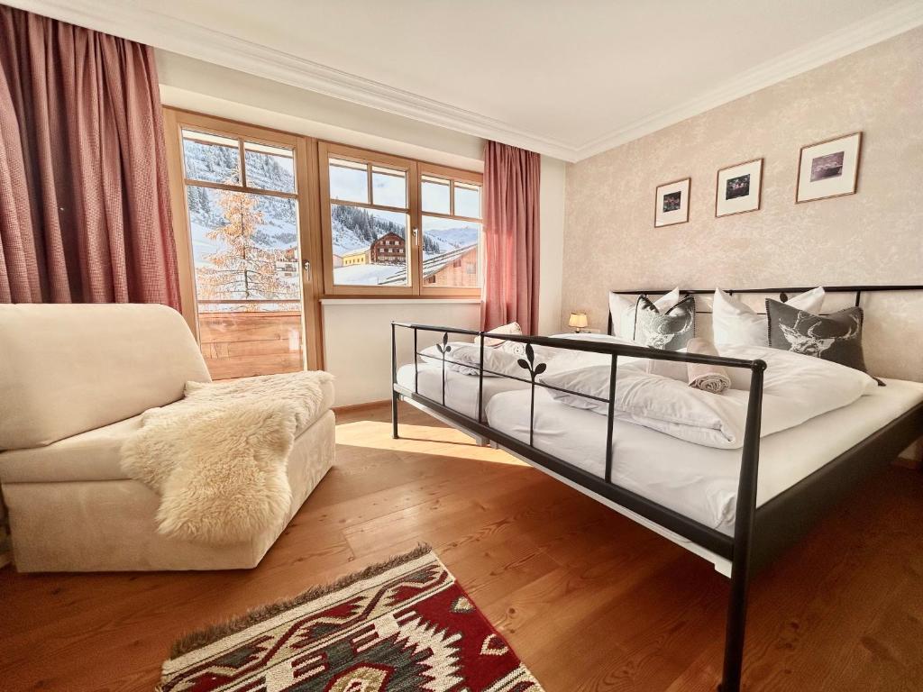 Hillside One - Ski-In Ski-Out Apartments am Arlberg في وارث ام ارلبرغ: غرفة نوم بسرير واريكة وكرسي
