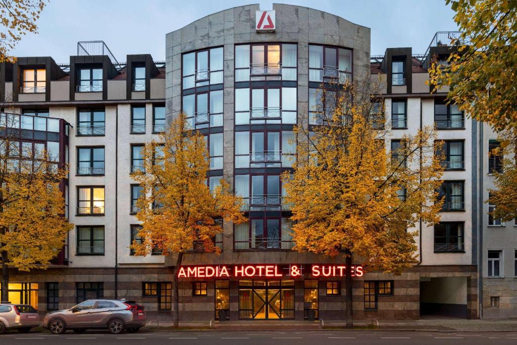 ein eckiges Hotel- und Suites-Gebäude mit vor dem Hotel geparkt in der Unterkunft Amedia Hotel & Suites Leipzig, Trademark Collection by Wyndham in Leipzig