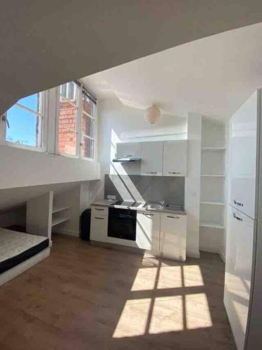 - une cuisine avec des appareils blancs et une fenêtre dans une chambre dans l'établissement La parenthèse lyonnaise, à Lyon