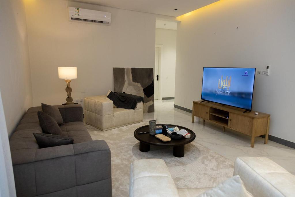 een woonkamer met een bank en een flatscreen-tv bij شقة بغرفتي نوم بتصميم أنيق مع مدخل خاص in Riyad