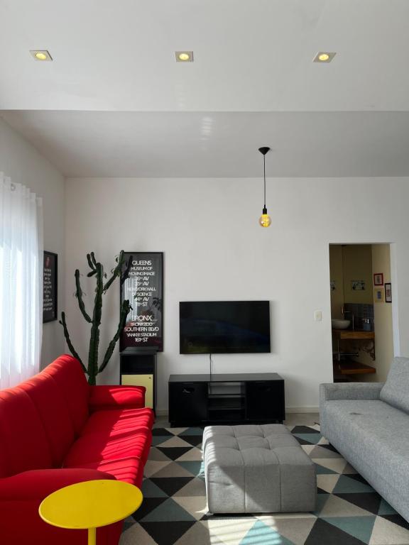 sala de estar con sofá rojo y TV en Santinho Ocean View House, en Florianópolis