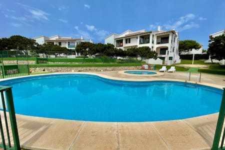 a large blue swimming pool in front of a house at BoschApartamento de 2 dormitorios y con piscina in Ciutadella