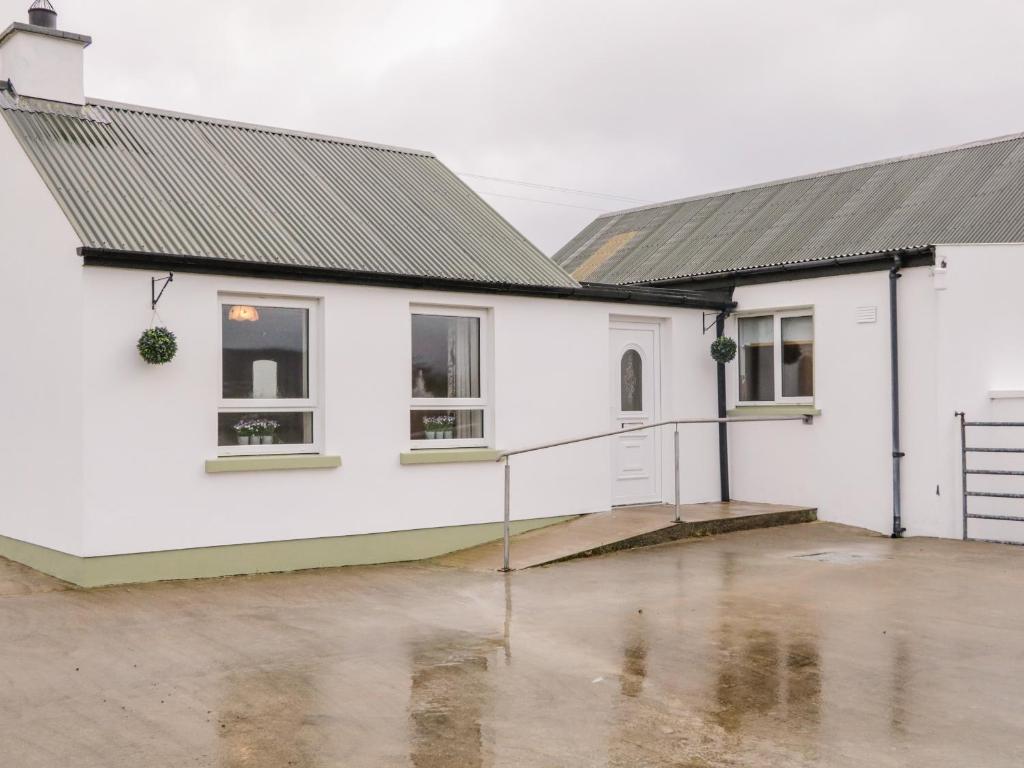 ein weißes Haus mit zwei Fenstern und einem Innenhof in der Unterkunft Fintan's in Carndonagh