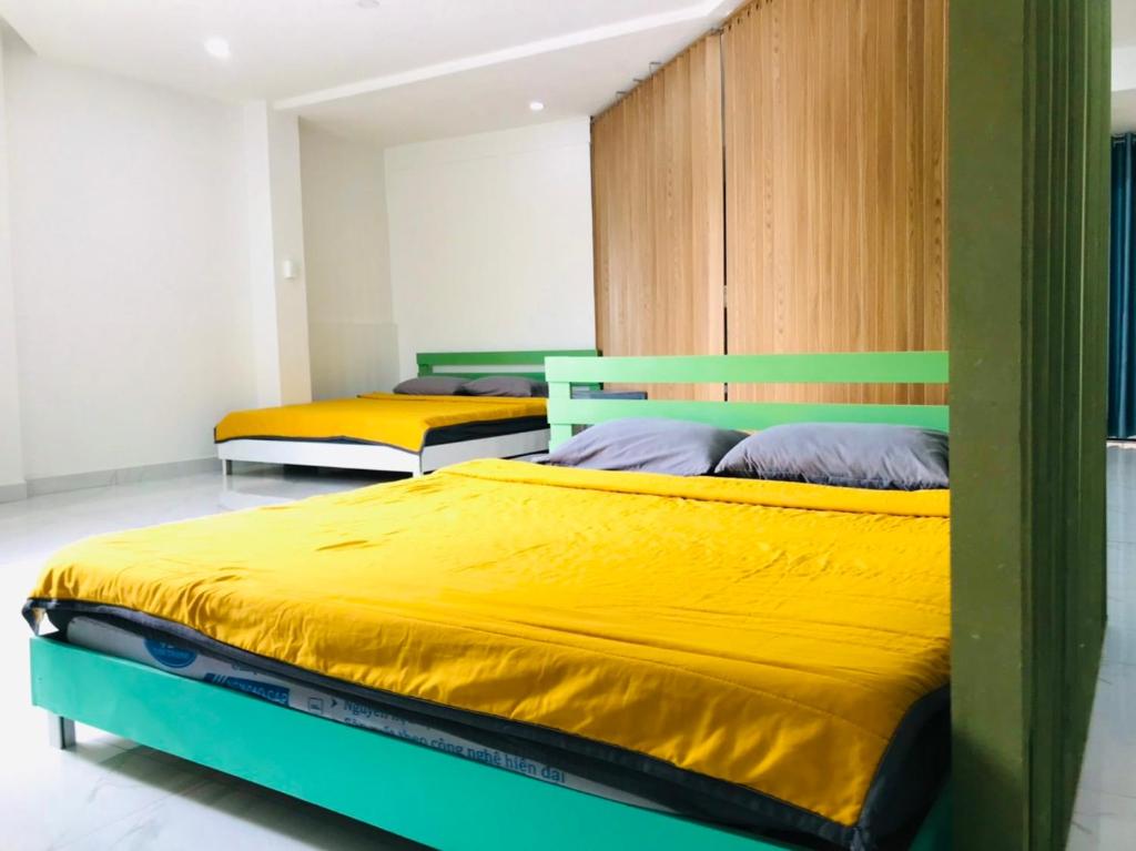 2 Betten in einem Zimmer mit Gelb und Grün in der Unterkunft NHÀ KHÁCH KEN in Cà Mau