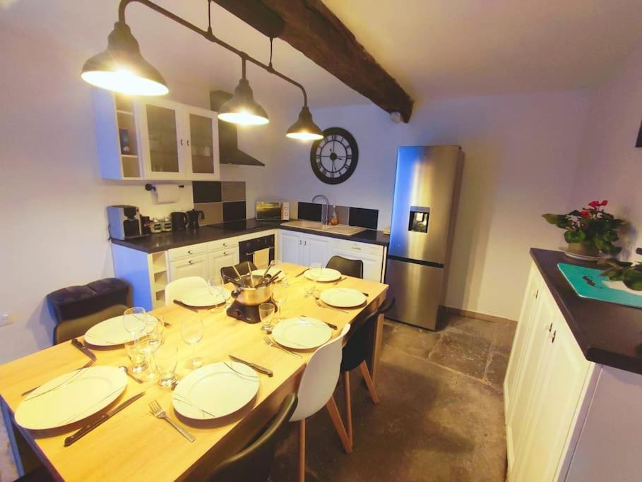 una cocina con una mesa de madera con platos. en Agréable maison 8 personnes WIFI et clim, en Marmeaux