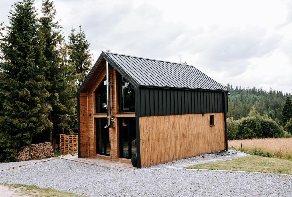 a small house with a black roof and wood at ArtHouse Podhale in Klikuszowa