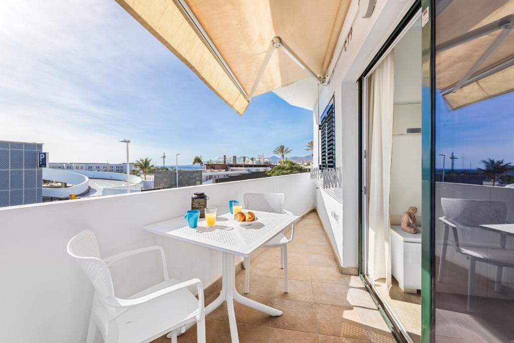 une table blanche et des chaises sur un balcon avec vue dans l'établissement Home2Book Modern Apt Puerto del Carmen, Terrace, à Puerto del Carmen