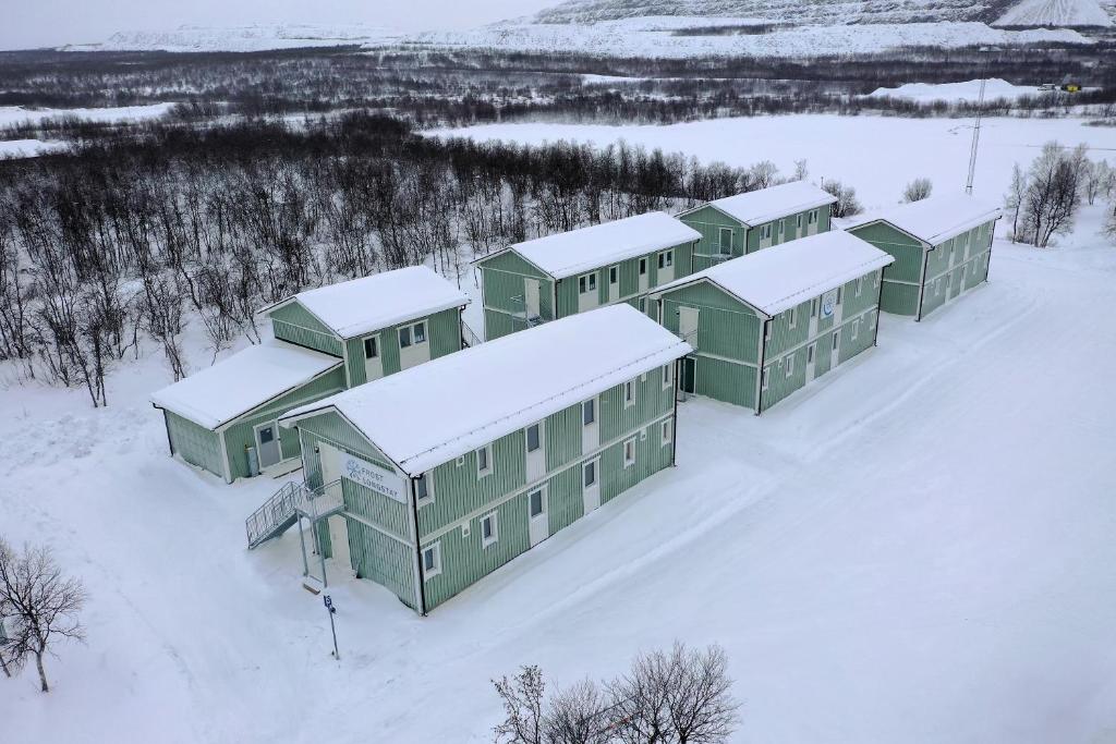 un groupe de bâtiments verts dans la neige dans l'établissement Frost Longstay Lombiavägen, à Kiruna