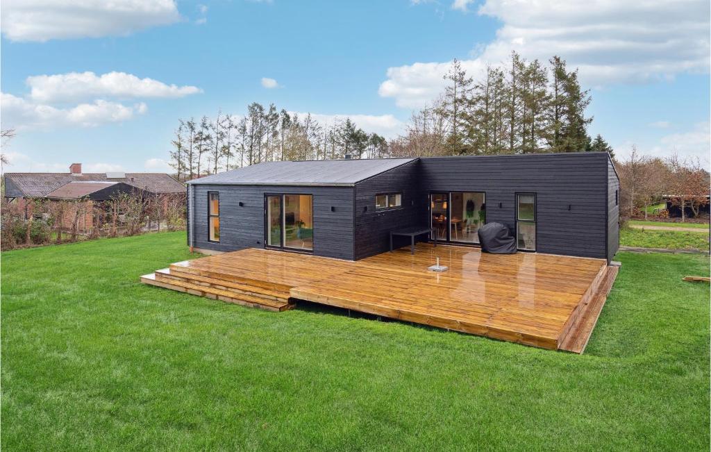 una pequeña casa negra con terraza de madera en Amazing Home In Spttrup With Wifi, en Spottrup