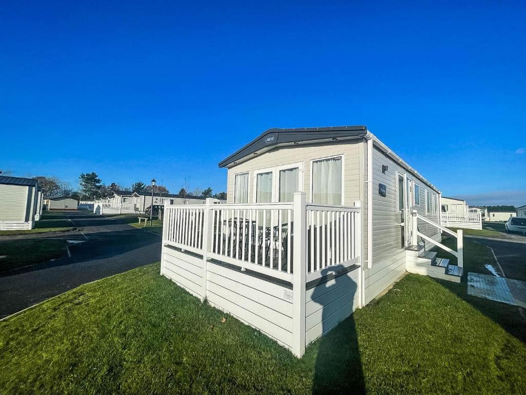 una pequeña casa con una valla blanca en el césped en Lovely Caravan With Decking At Carlton Meres Holiday Park In Suffolk Ref 60023ch en Saxmundham