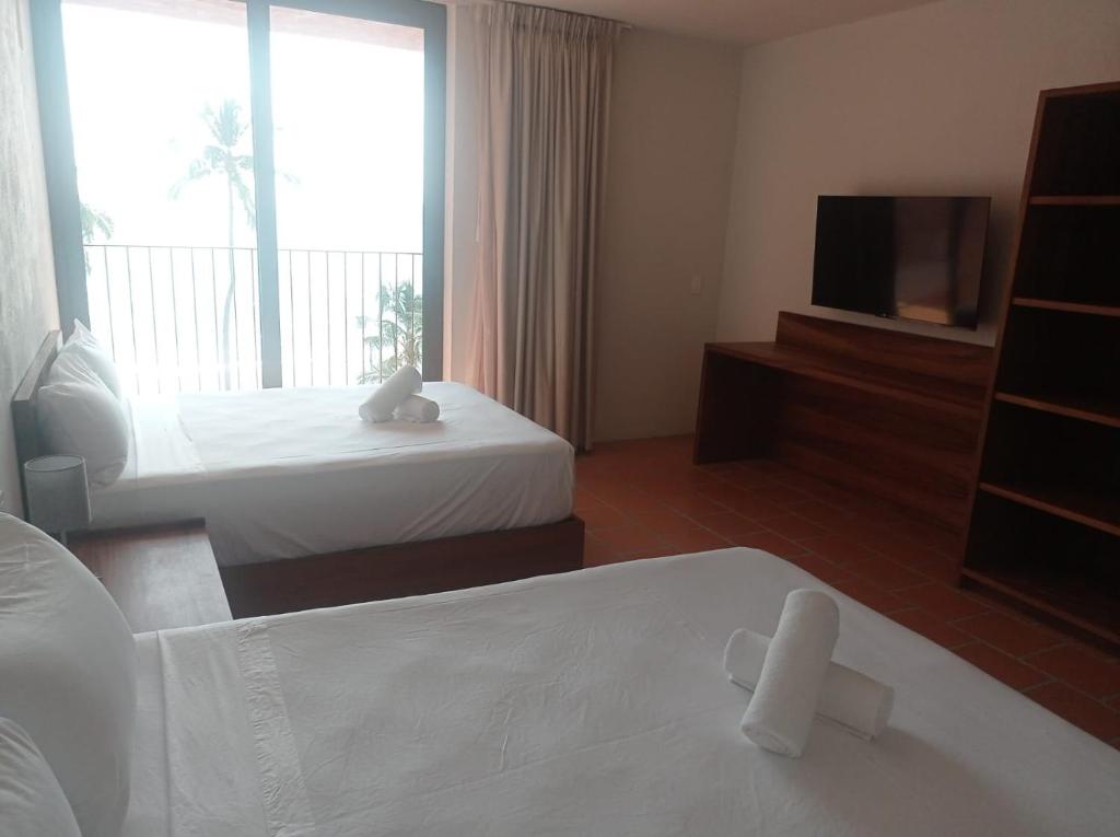 Cette chambre comprend deux lits et une télévision. dans l'établissement HOTEL AURELIA, à San Patricio - Melaque
