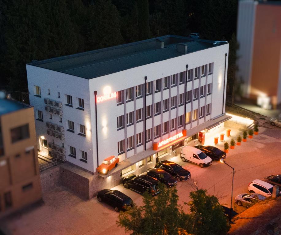 un gran edificio blanco con coches aparcados en un aparcamiento en DORM BG pet-friendly Aparthotel, en Stara Zagora