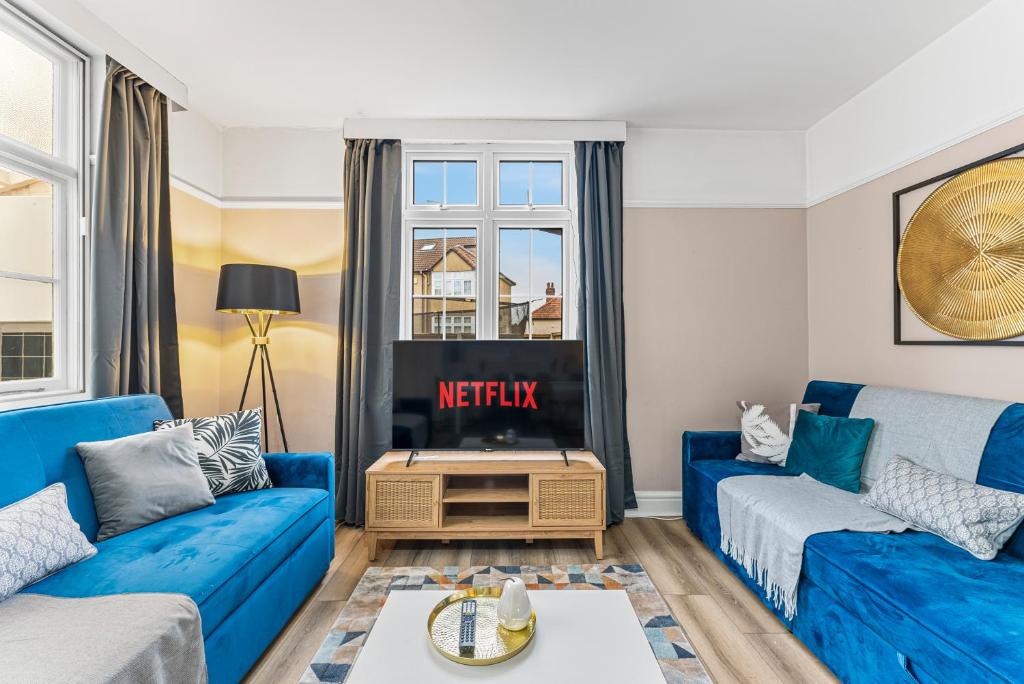 uma sala de estar com sofás azuis e uma televisão em Stunning 4-bed - Garden - Sleeps 14 em Bristol