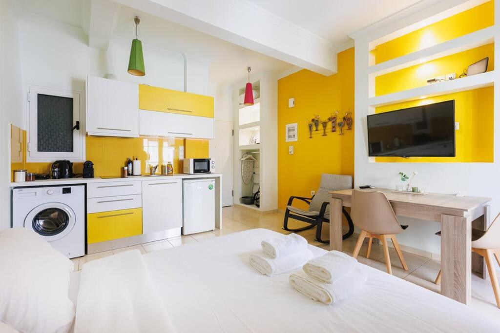 una cocina con paredes blancas y amarillas y una mesa. en Relaxing studio in Athens city center, en Atenas