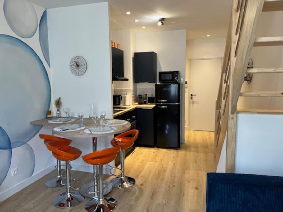 a kitchen with a table and some orange chairs at Le Bubble - Centre Ville - La Bonne Marienne in Angers