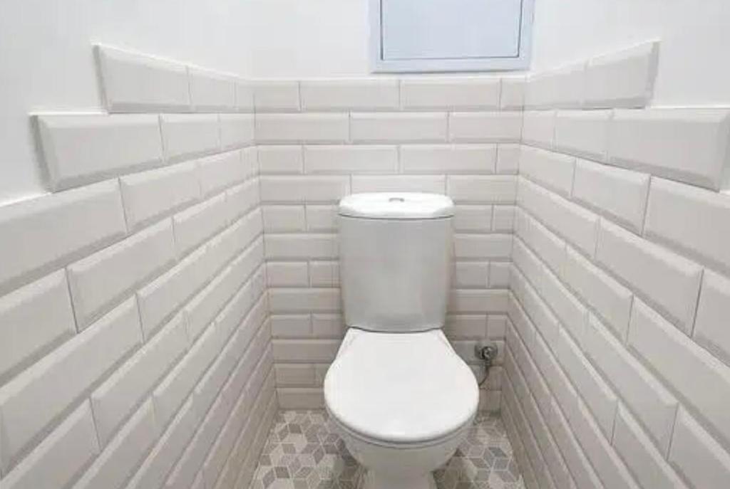 een wit toilet in een badkamer met witte tegels bij VIP apart 560 in Tbilisi City