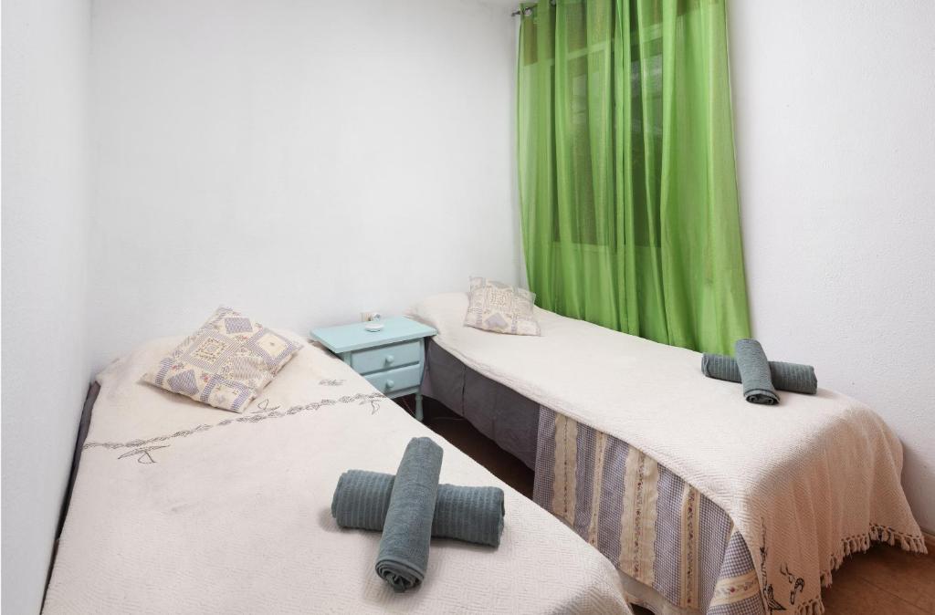 two twin beds in a room with green curtains at Senda el Cantal 3habitaciones Beach in Cala del Moral