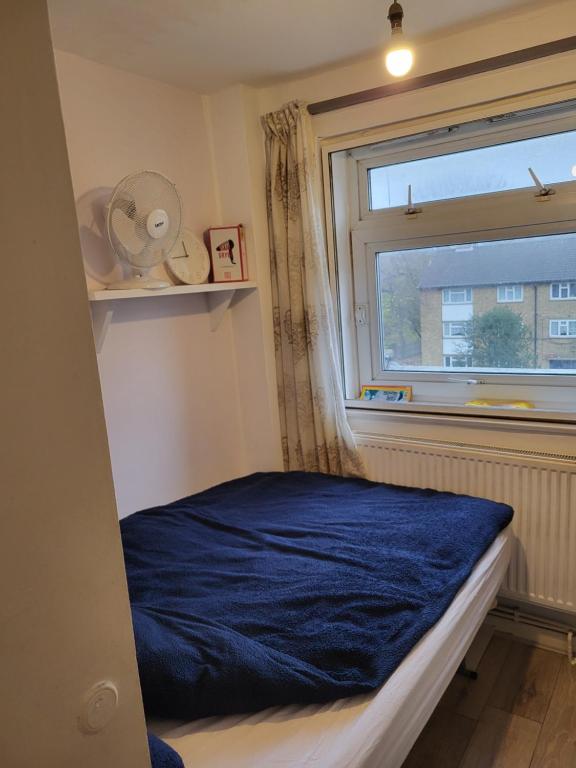 a bedroom with a blue bed and a window at COSY ROOM 2 LONDOn in London