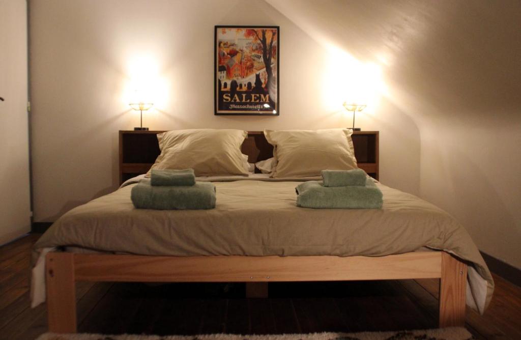 une chambre avec un grand lit avec deux oreillers dessus dans l'établissement Gîte du Chat noir (Brocéliande), à Campénéac