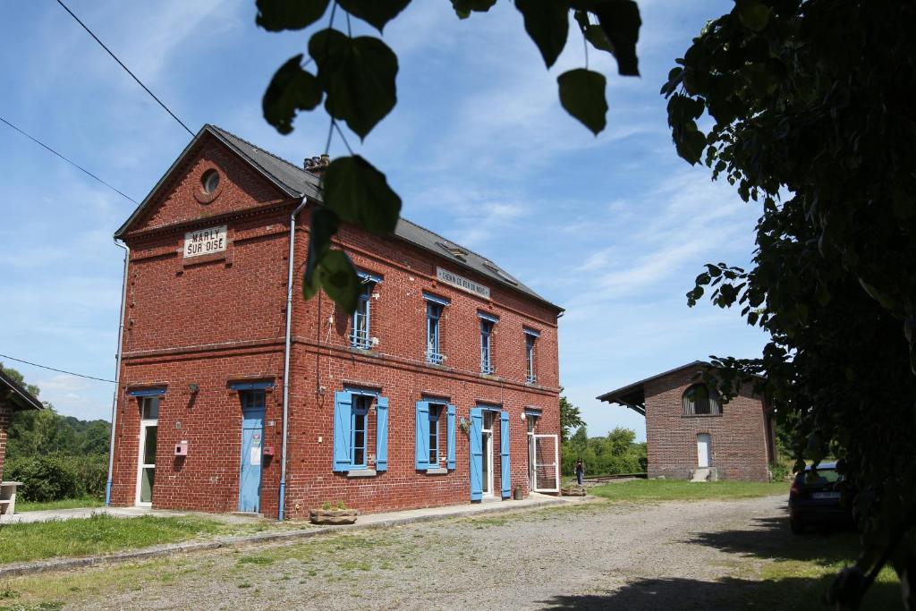 um antigo edifício de tijolos vermelhos com portas e janelas azuis em Les Pommes d'Or em Marly-Gomont