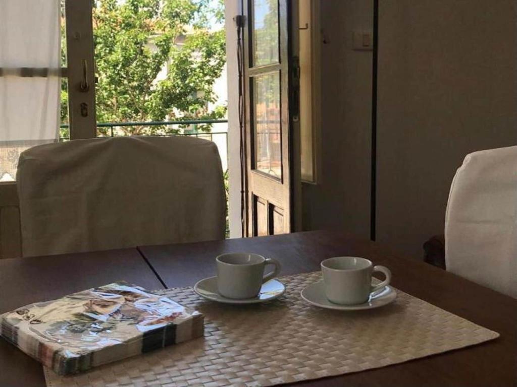 un tavolo con due tazze di caffè e un libro sopra di Cozy Apartment in Torrenova in a delightful area a Torrenova