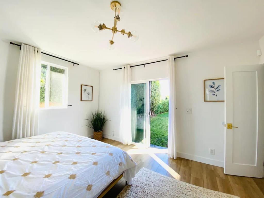 een witte slaapkamer met een bed en een raam bij Charming 3 BR Home Near SoFi and LAX - 65th in Los Angeles