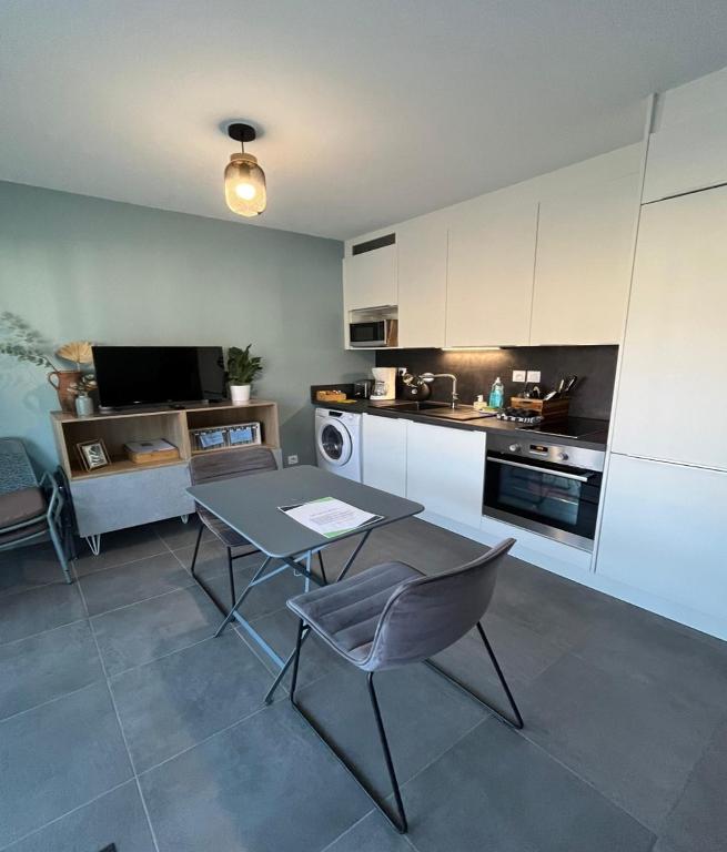 une cuisine avec une table et des chaises dans une pièce dans l'établissement Studio Hermine neuf pour 2 personnes au cœur de St, à Saint-Malo