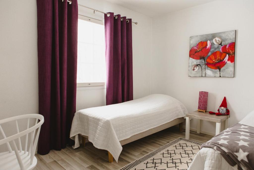 a bedroom with a bed and a window with purple curtains at Paritalohuoneisto lähellä Joulupukin Pajakylää in Rovaniemi