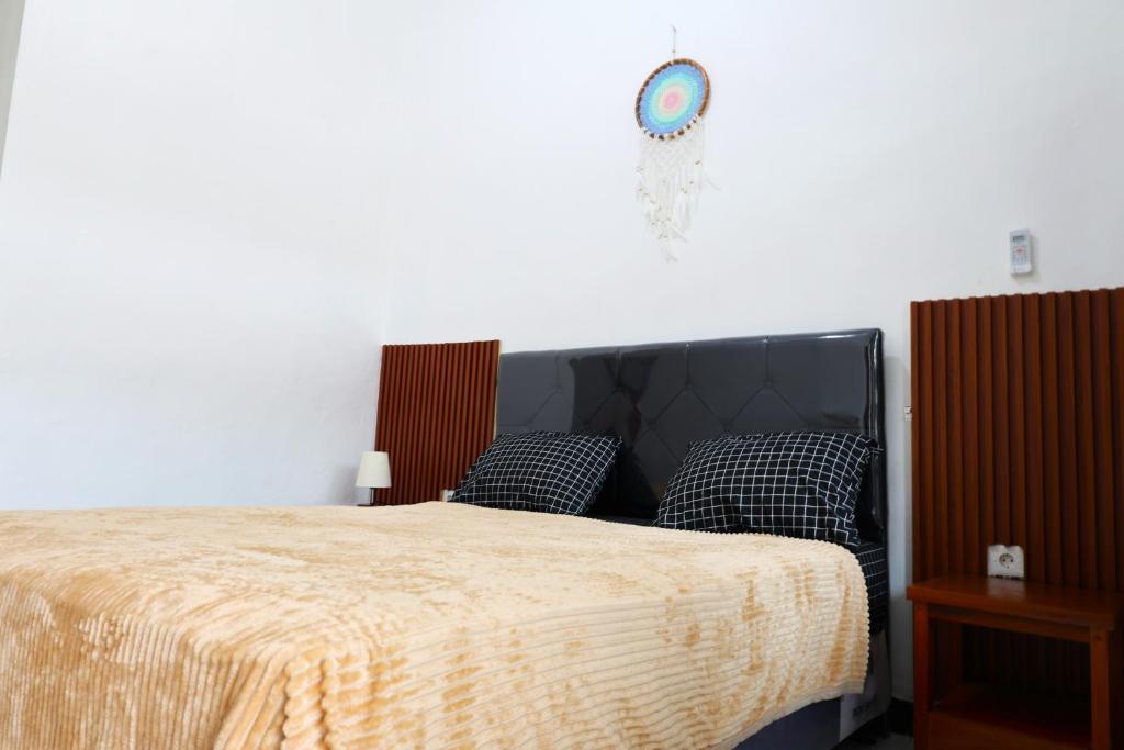 1 dormitorio con 1 cama y reloj en la pared en Pondok Dete Guesthouse en Sanur