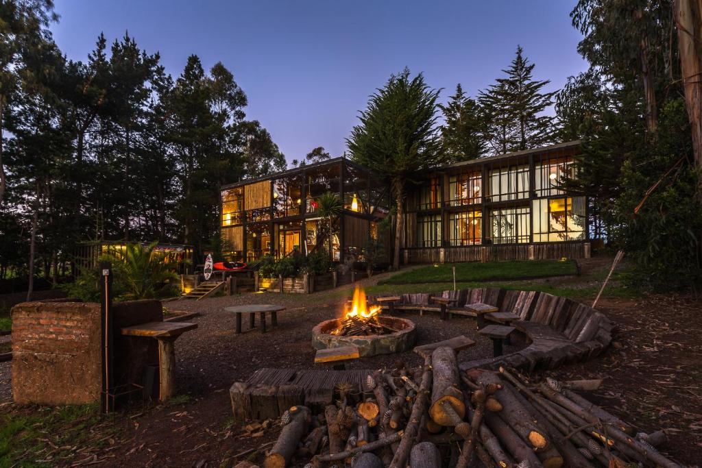 une maison avec un foyer extérieur en face de celle-ci dans l'établissement Surf Lodge Punta de Lobos, à Pichilemu