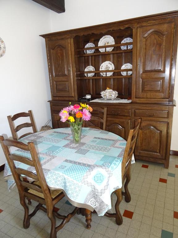 a dining room table with a vase of flowers on it at Le Clos Fleuri in Caumont