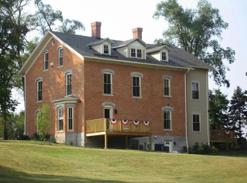 ein großes Backsteinhaus mit einem Balkon auf einer Wiese in der Unterkunft Furness Mansion in Chesterton