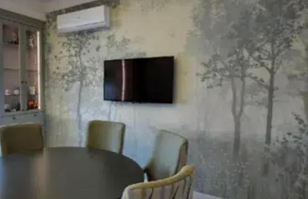 mesa con sillas y TV en la pared en VIP apart 565, en Tiflis