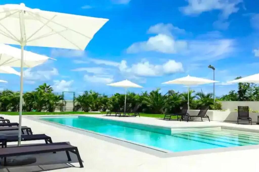 a swimming pool with umbrellas and chairs and a pool at Maho: Cozy Studio with pool&gym in Maho Reef