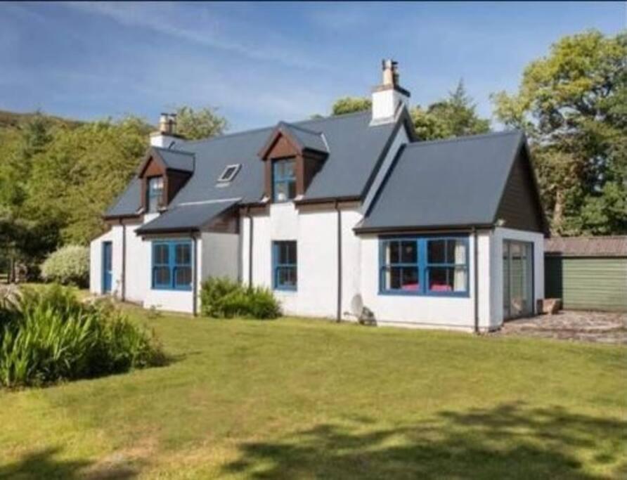 a white house with a black roof on a yard at Alltcreich in Craignure
