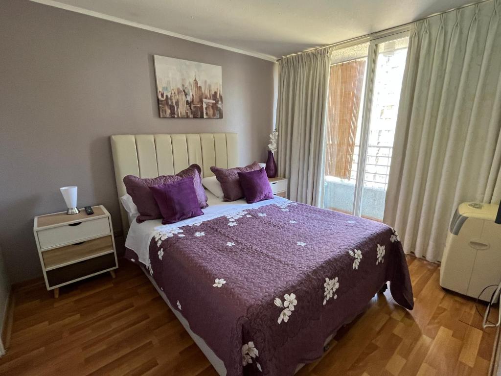 a bedroom with a bed with purple sheets and a window at Amoblados ChileRent Sto domingo in Santiago