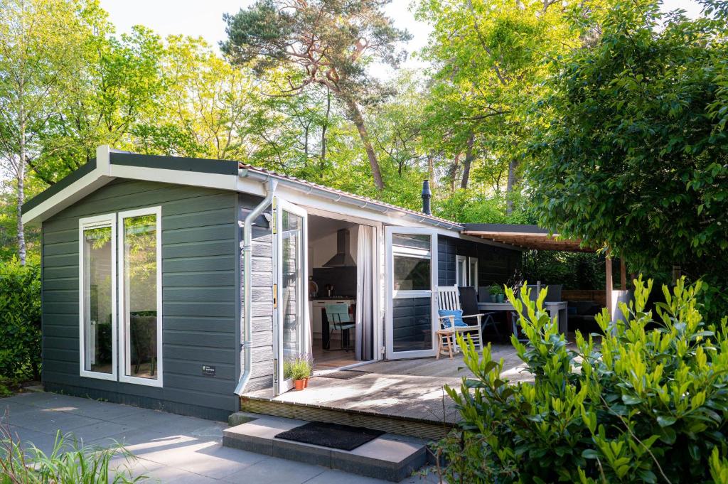 Casa pequeña verde con porche y patio en Lodge Vlinder Nunspeet Veluwe, en Nunspeet