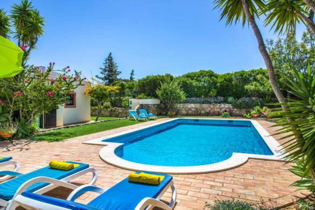 una piscina con due sedie a sdraio blu e una piscina di Amazing 3 bedroom Villa in Carvoeiro! a Carvoeiro