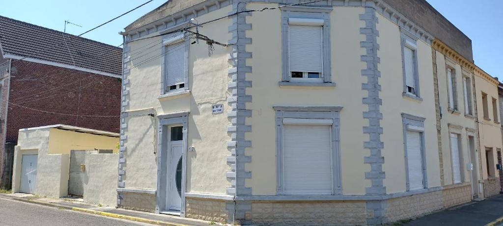 a brick building with shuttered windows on a street at Maison 8 personnes in Vendin-le-Vieil