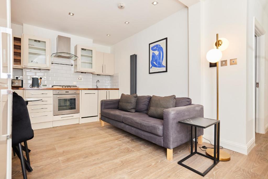 a living room with a couch and a kitchen at The Bermondsey Place - Cozy 2BDR Flat in London