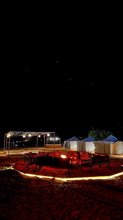 a group of tables and tents on a beach at night at Almansour farm in Al-ʿUla