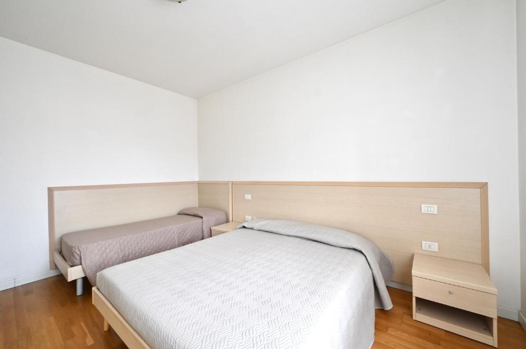 Cet hébergement comprend 2 lits dans une chambre dotée de murs blancs et de parquet. dans l'établissement Tiepolo Apartments, à Lido di Jesolo