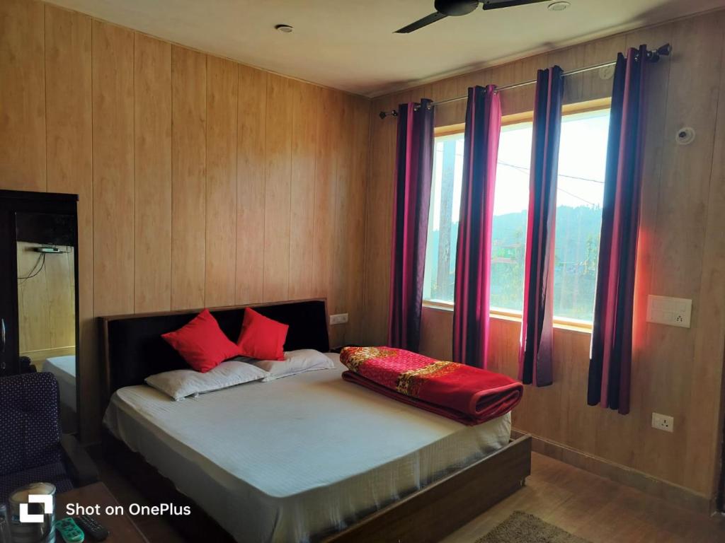 a bedroom with a bed with red pillows and a window at Silver Dew Resorts and Restaurant in Dhanaulti